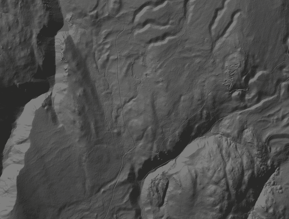 Hillshade of a LiDAR elevation tile: a valley floor between steep walls, with side drainages.